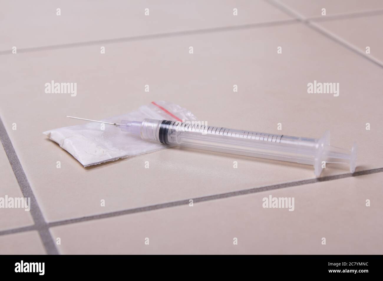 drug syringe and heroin powder on tiled floor Stock Photo