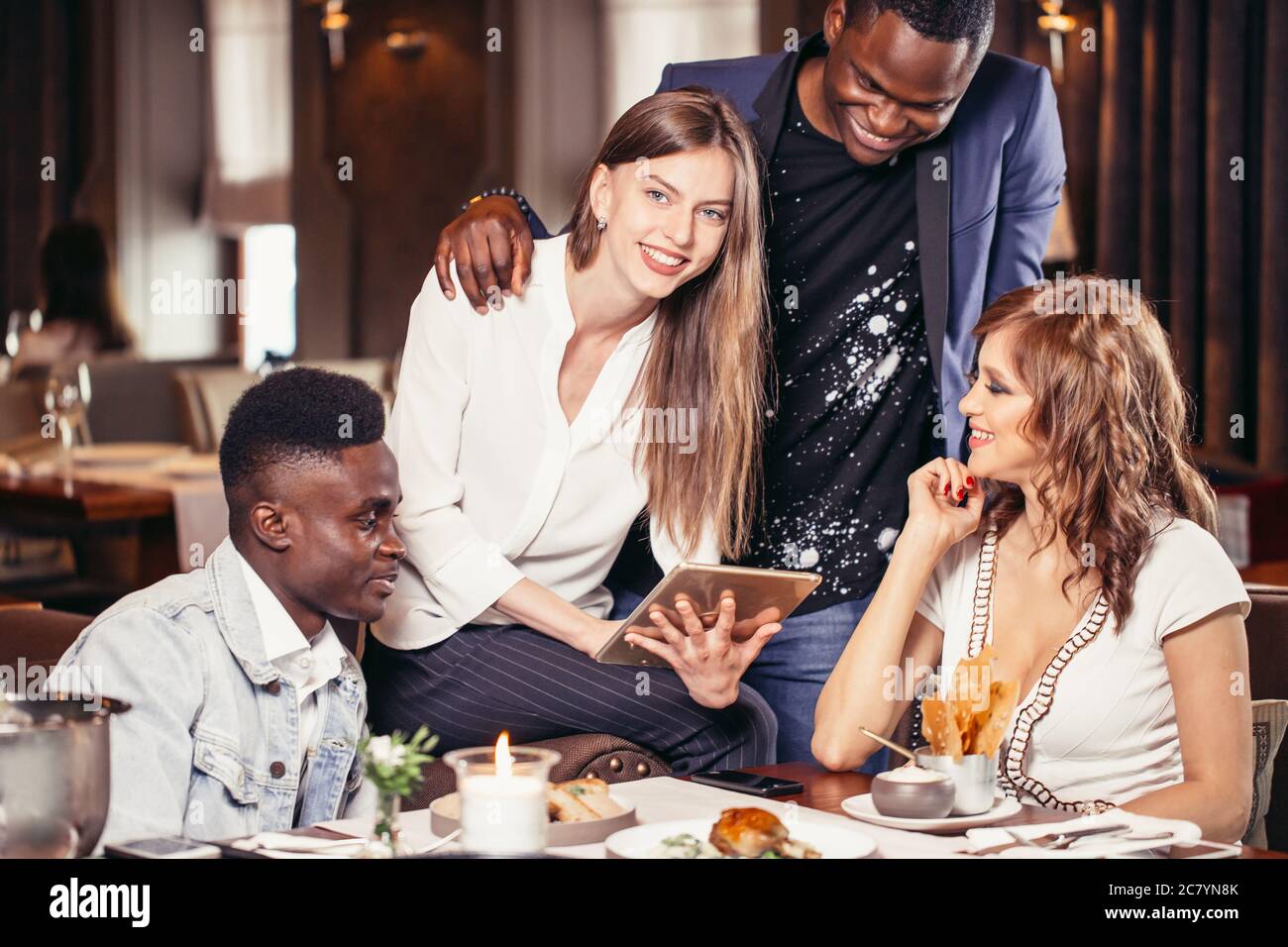 Two mixed couples having a good time at restaurant talking about future vacations Stock Photo