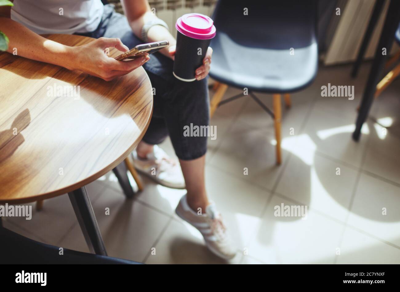 Female holding paper cup of coffee and smart phone in cafe. Coffee break.Blurred image,selective focus Stock Photo