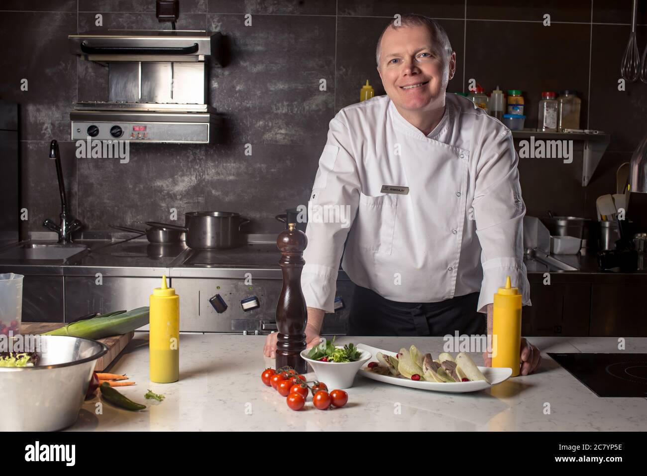 Portrait of a smiling male chef with cooked food standing in the ...