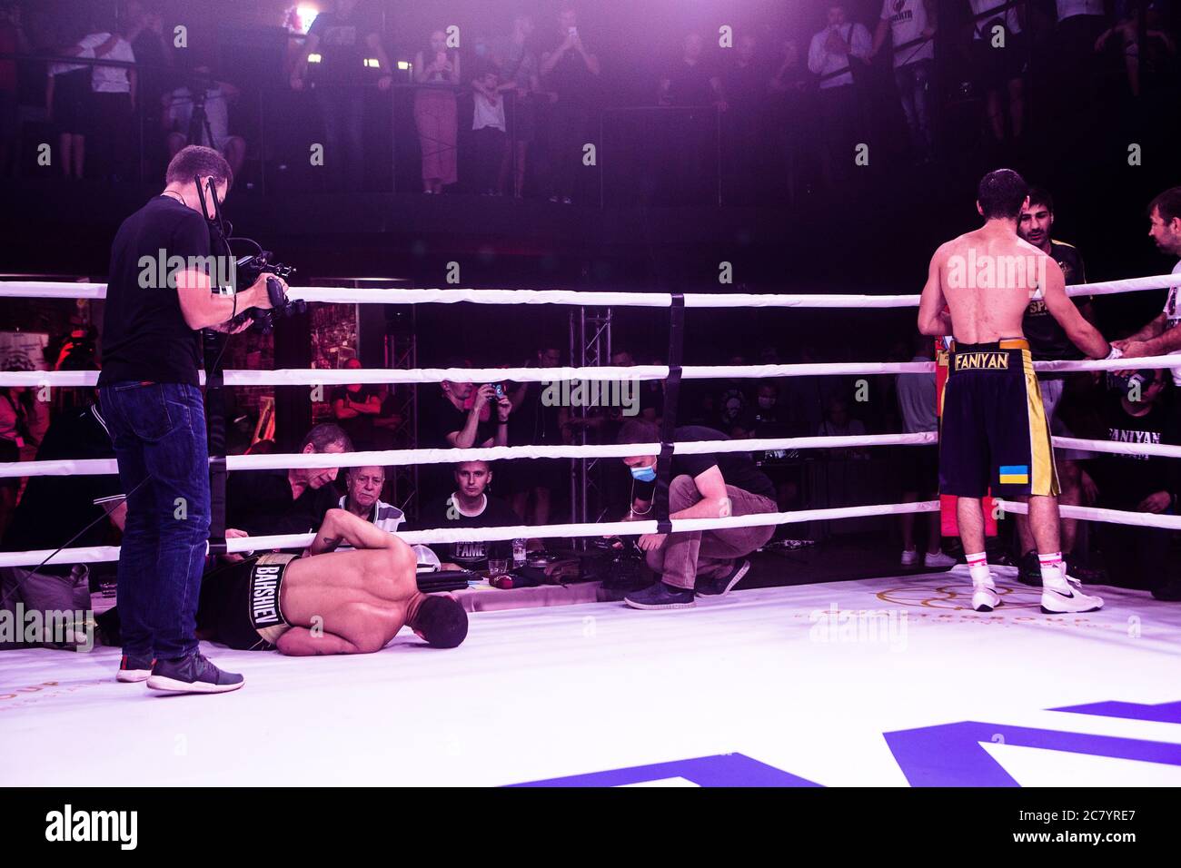 Ukraine based boxer Aram Fanian in his corner with Azeri boxer from Balarus N.Bahshiev suffering from bitter knock out from body punch, doc helps him. Stock Photo