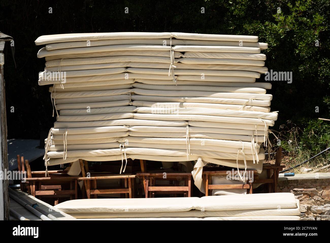 A high pile of beige mattresses for sunbeds is waiting to be used by summer tourists. Stock Photo