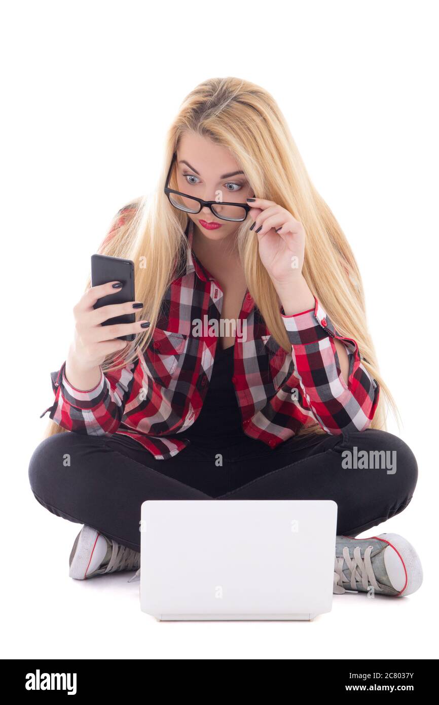 young astonished blondie woman sitting with laptop and mobile phone isolated on white background Stock Photo