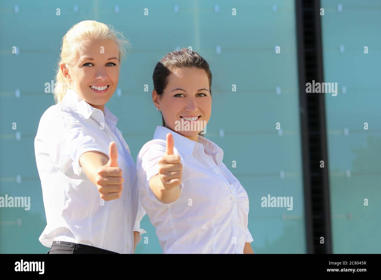 portrait of two young attractive business women with thumb up Stock ...