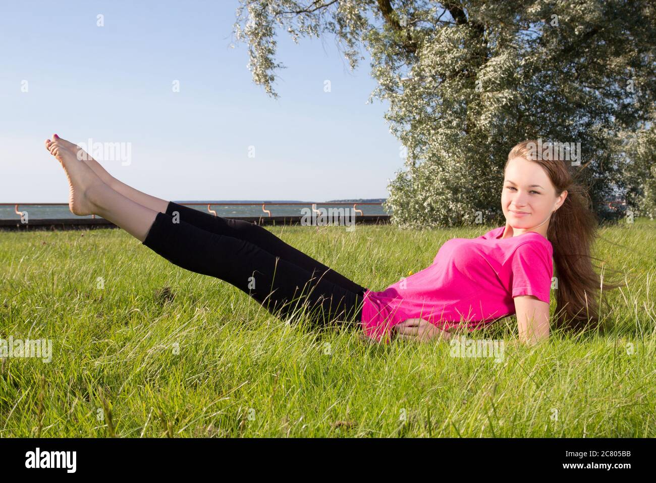 Young woman exercising in park on the grass Stock Photo - Alamy