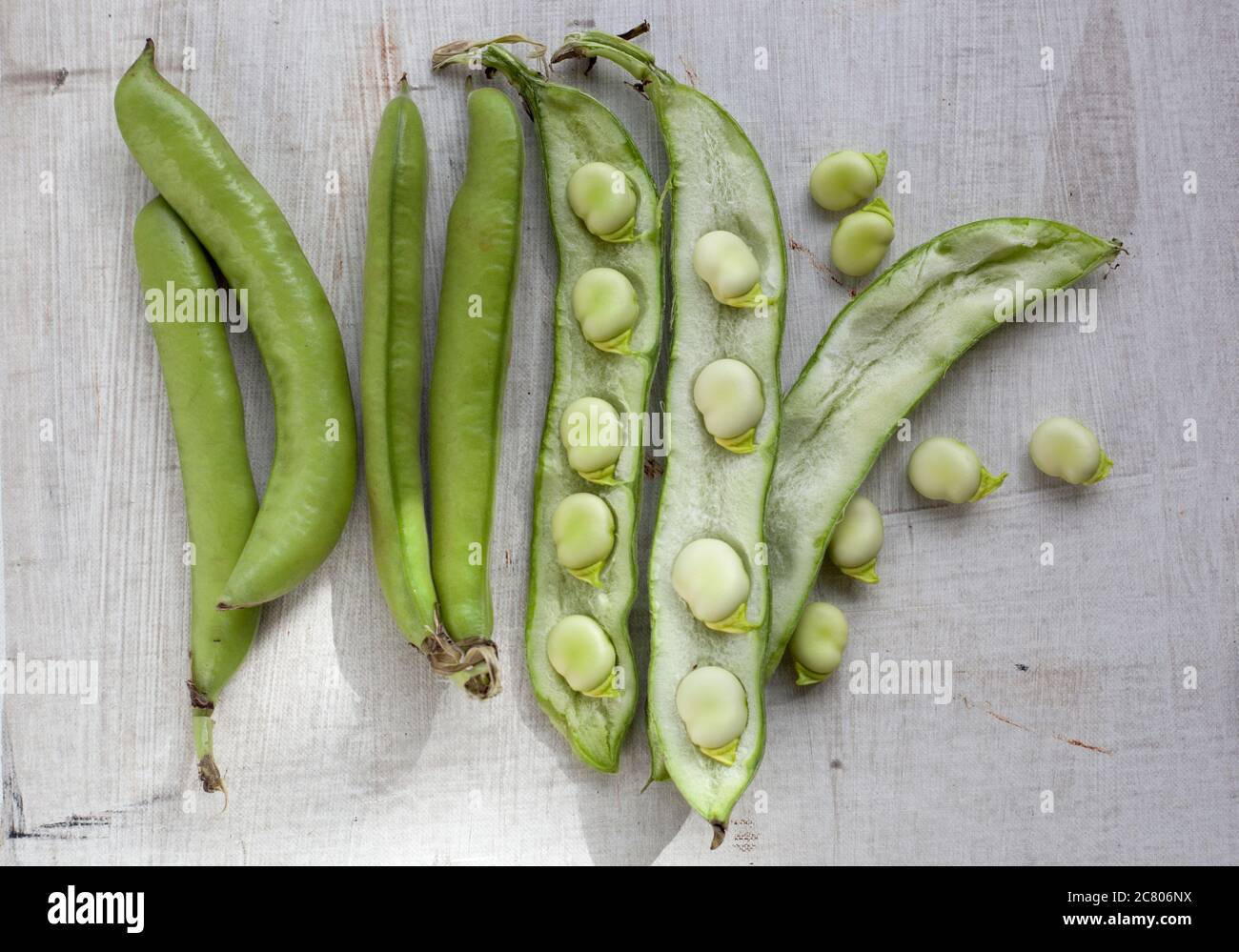 A close up of broad beans some open in their shells on a table top Stock Photo