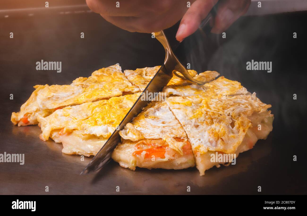 Japanese pizza okonomiyaki cooking on hot plate teppanyaki style Stock