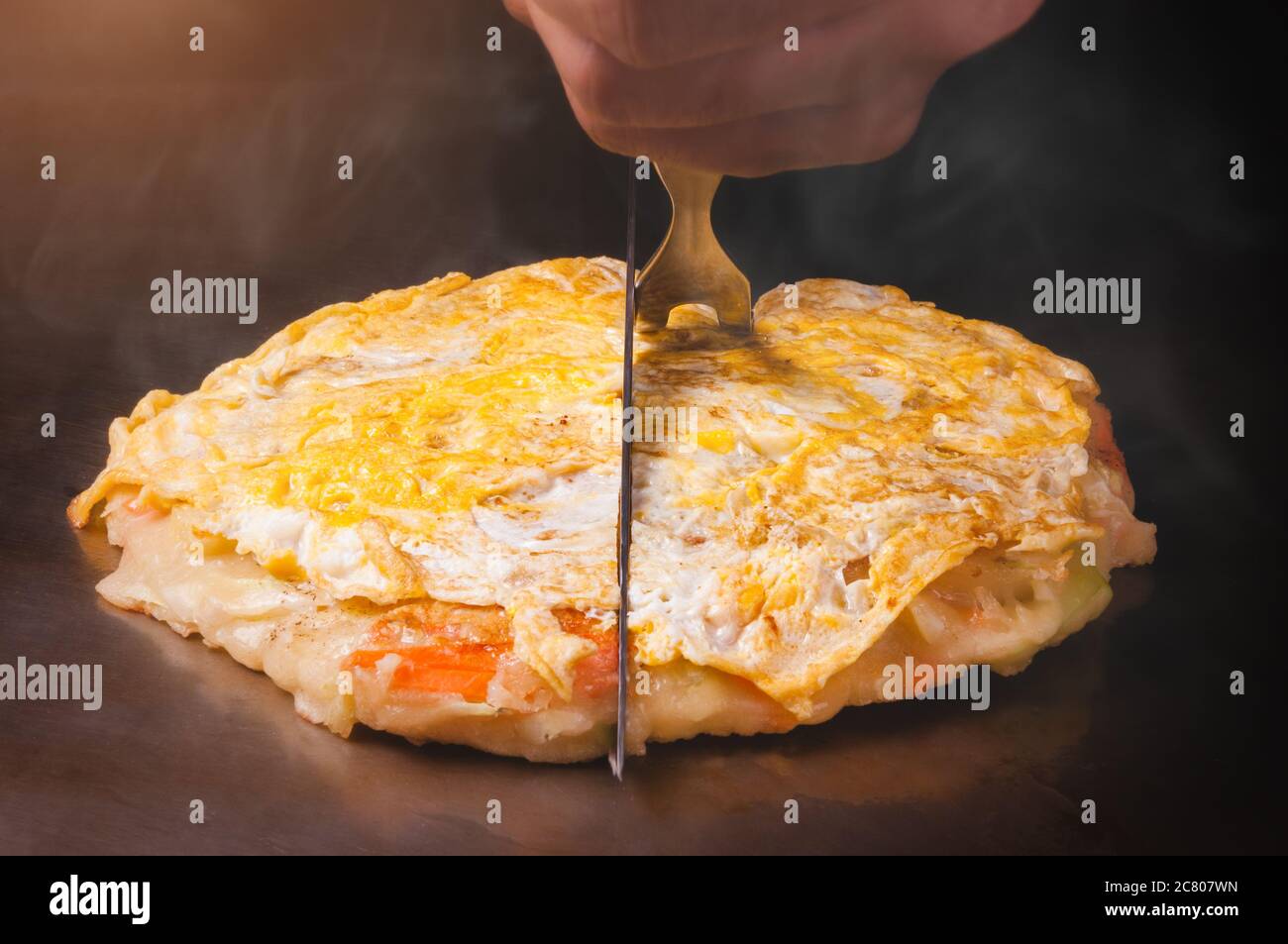 Japanese pizza okonomiyaki cooking on hot plate teppanyaki style Stock