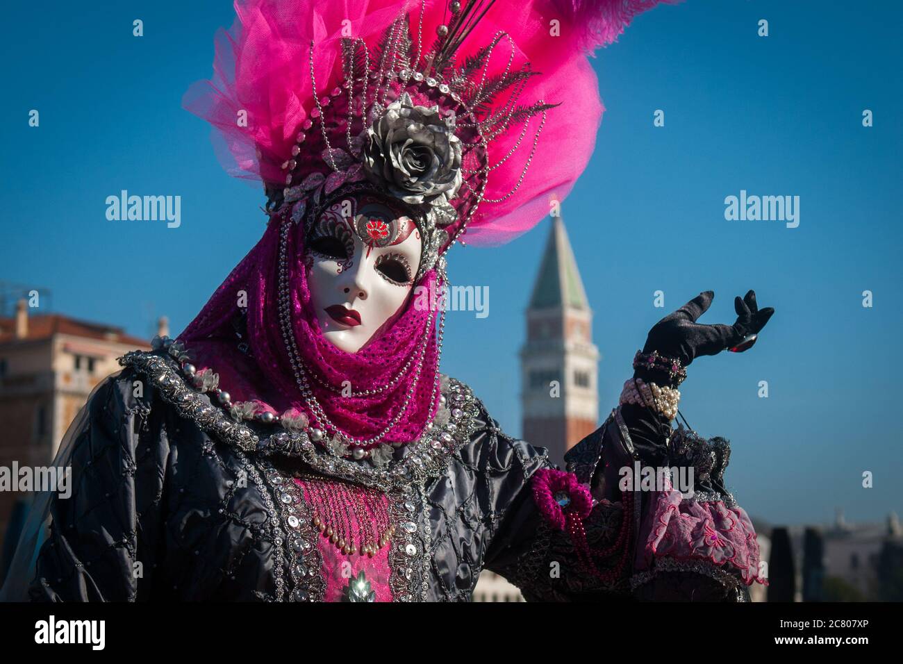 VENICE, ITALY - 28 FEBRUARY 2019: a purple dame costume during Venice Carnival poses with San Marco in background Stock Photo