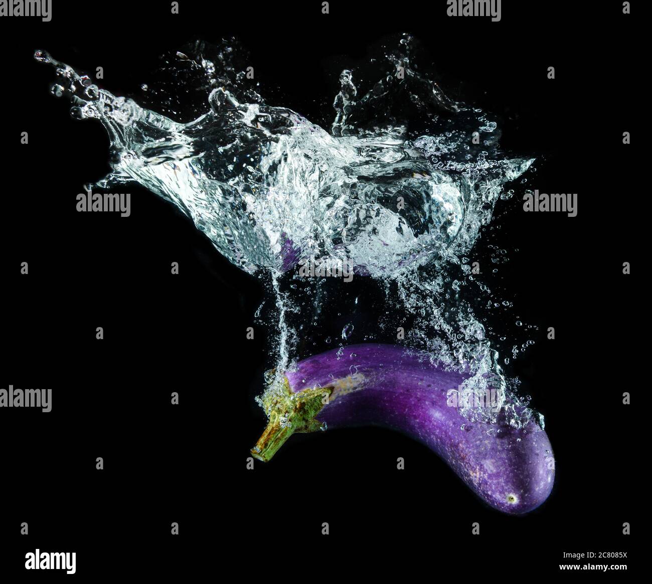 Water splashing and purple eggplant with black background Stock Photo