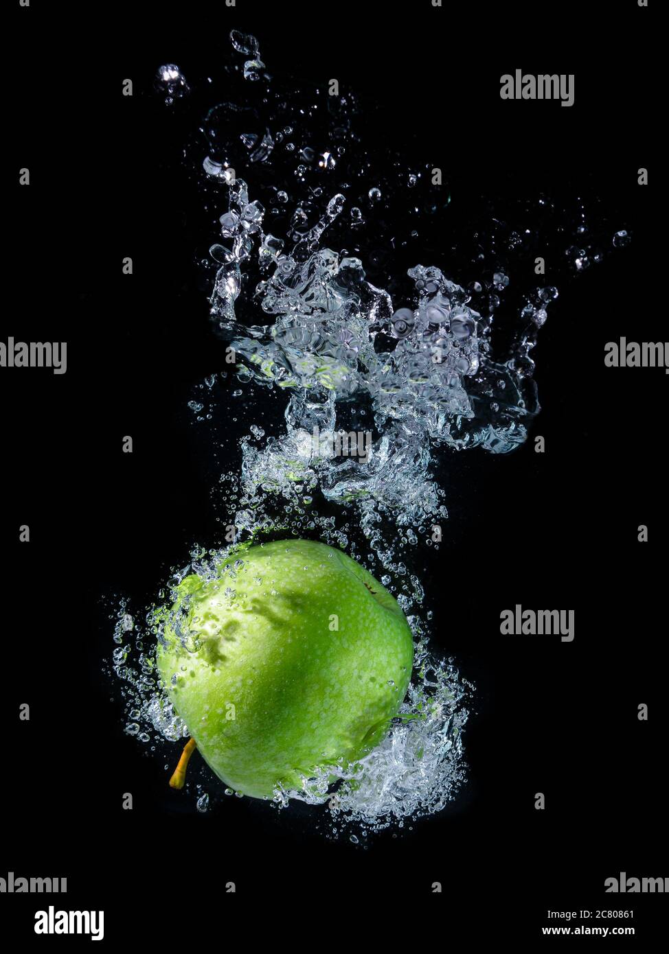 Water splashing and green apple with black background. Stock Photo