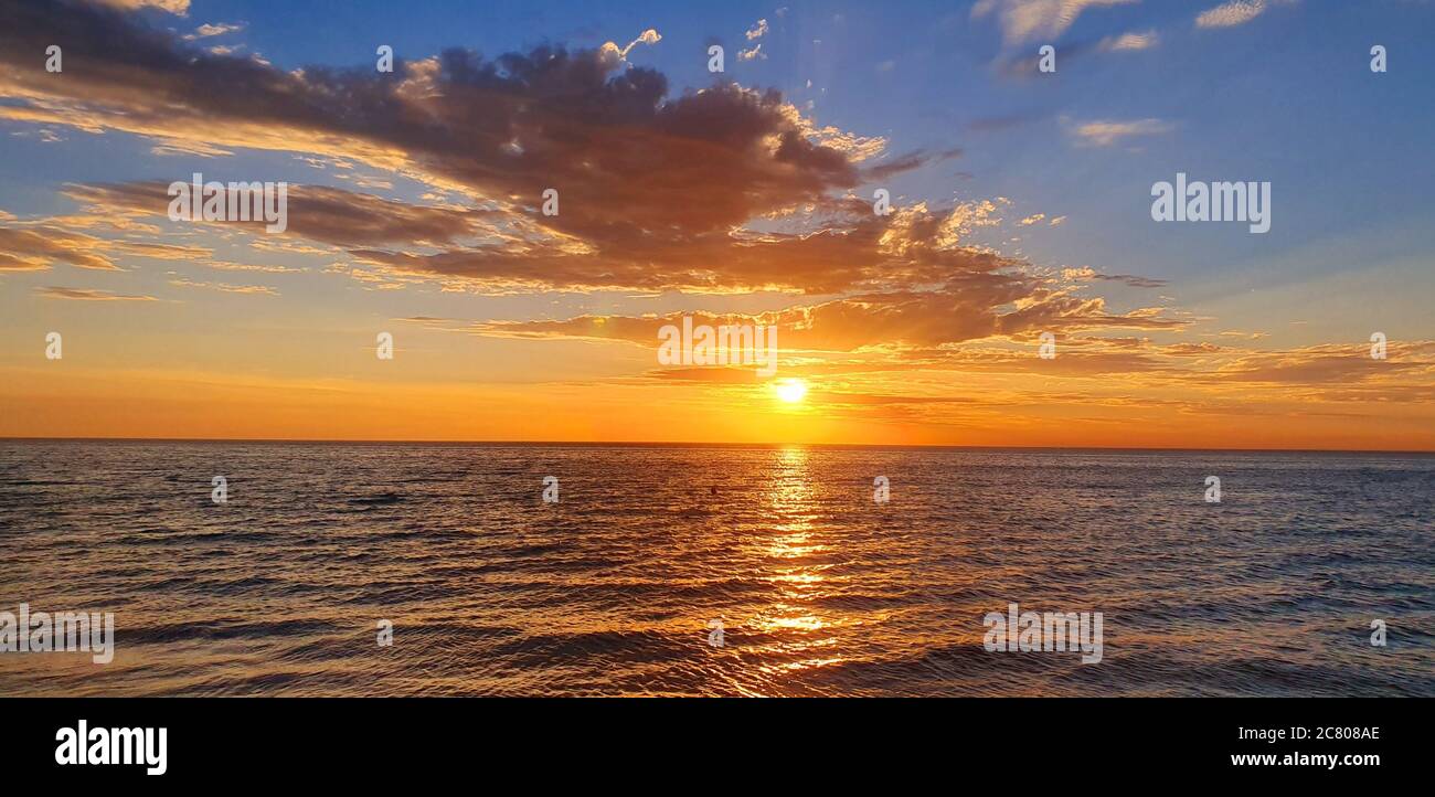 Beautiful sunset captured at the sea with a cloudy sky Stock Photo - Alamy