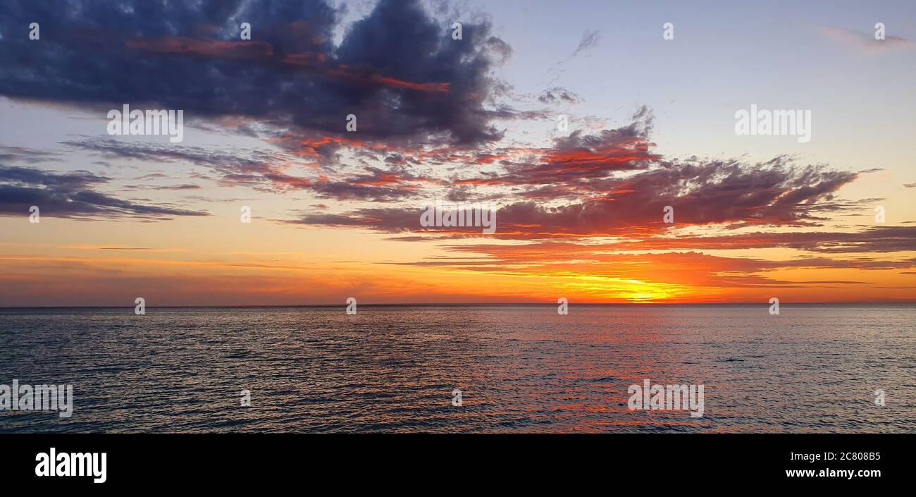 Beautiful sunset captured at the sea with a cloudy sky Stock Photo - Alamy