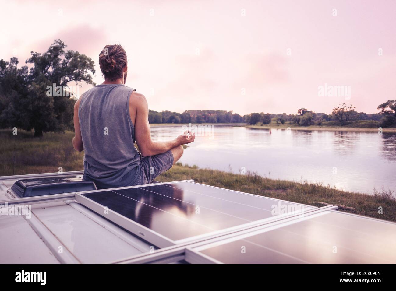 Man meditating on the roof of a camper van Stock Photo