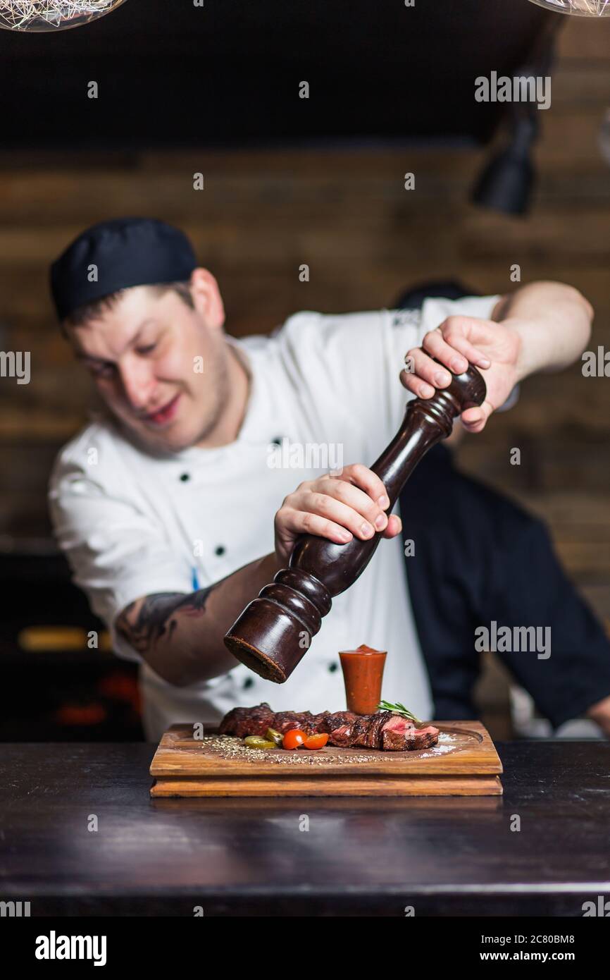Chef sprinkling spices on dish in commercial kitchen Stock Photo