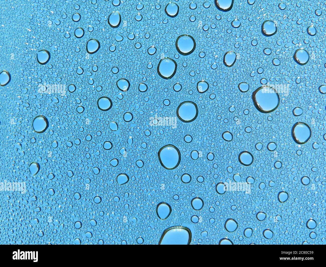 Closeup shot of water drops on a glass surface with blue textures Stock ...