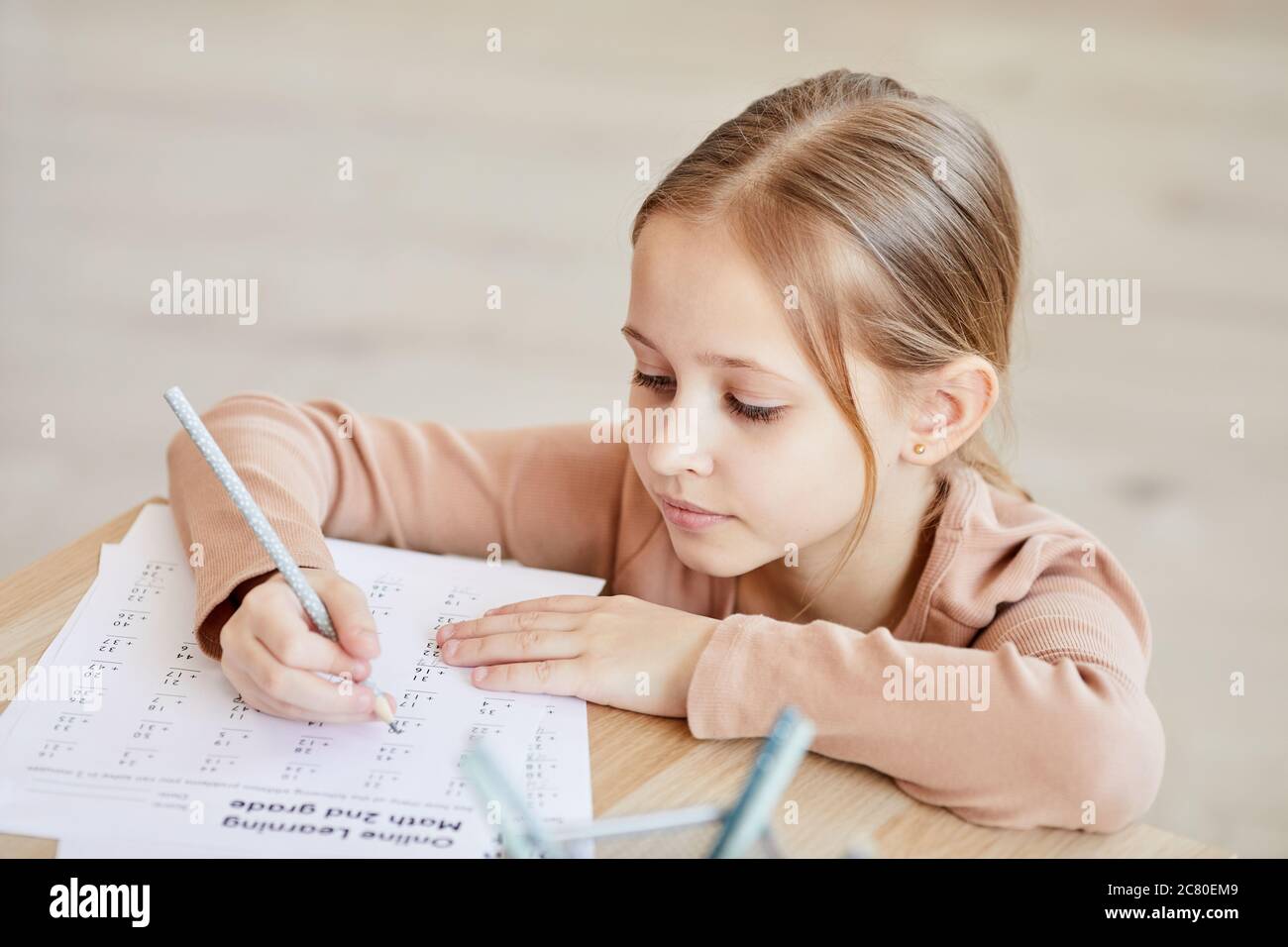 High angle portrait of cute little girl doing math test for online
