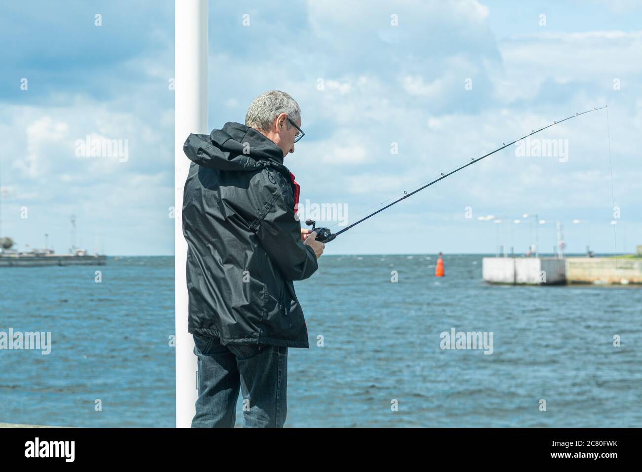 A middle-aged man, 50 plus, with a fishing rod. Fishing is one of the safe activities during the coronavirus pandemic. It is an outdoor activity and it includes social distance Stock Photo