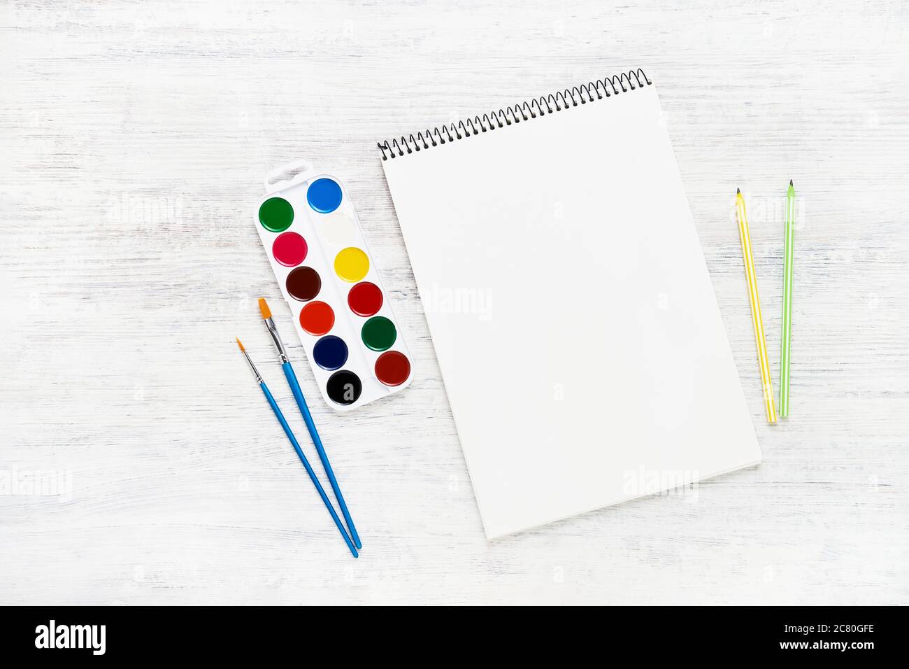 painting mockup.blank sketchbook, paintbrushes and paints on yellow wooden  board background. Creative artist workplace flat lay. top view on table  with Blank notebook with drawing tools. Stock Photo