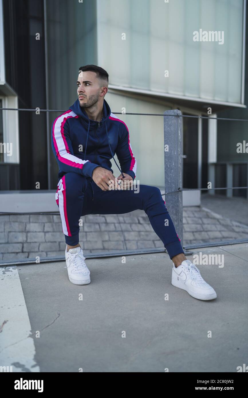 Vertical shot of Caucasian male with tattoos posing with building in the background Stock Photo