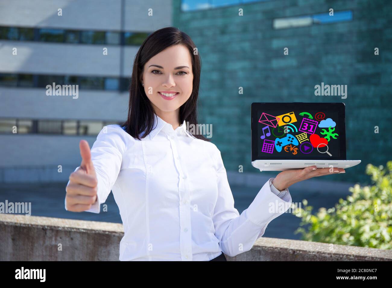 young beautiful business woman showing laptop with colorful media icons ...