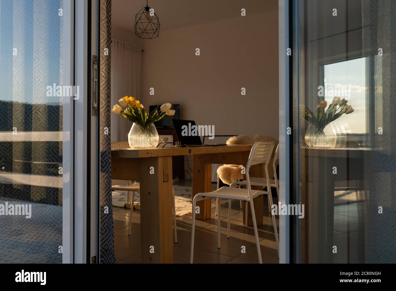 Modern room design. Interior of light dining room decorated with flowers. Laptop on a table Stock Photo