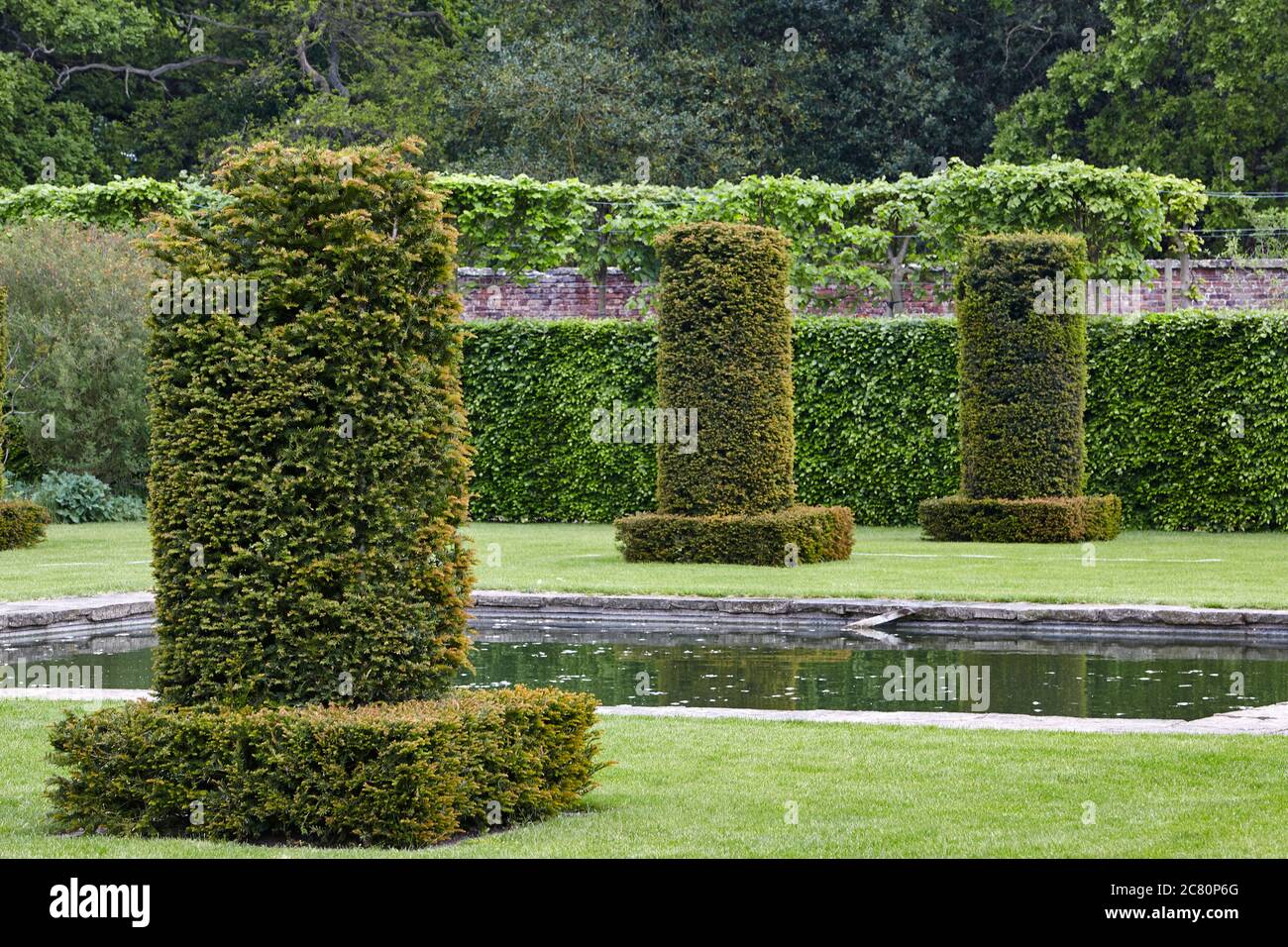 Yew columns by the reflective pond designed by the dutch garden architect Piet Oudolf in the Silent Garden at Scampston Hall Stock Photo