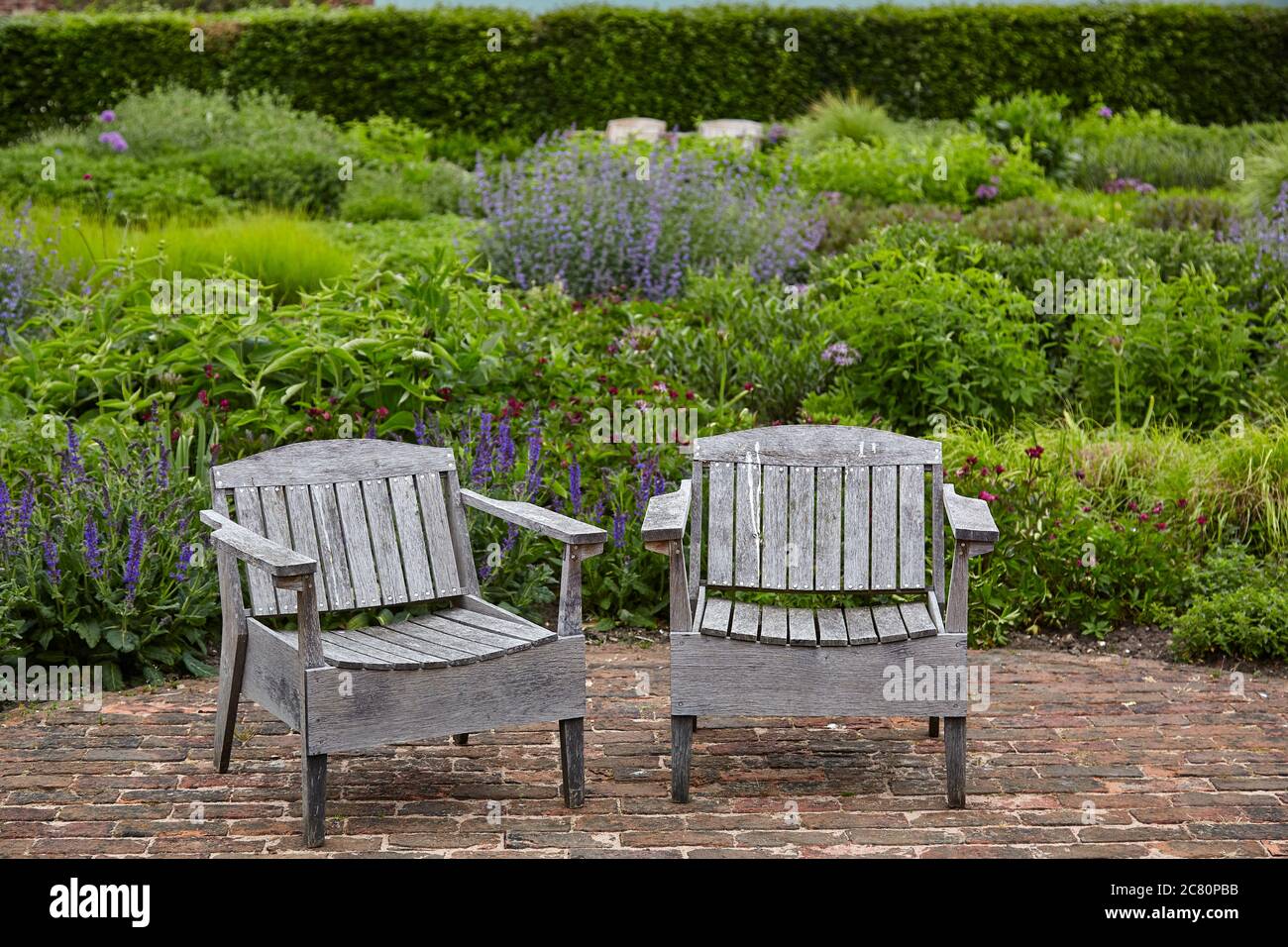 Two wooden garden chairs on paved terrace in the Walled Garden at Scampston Hall Stock Photo