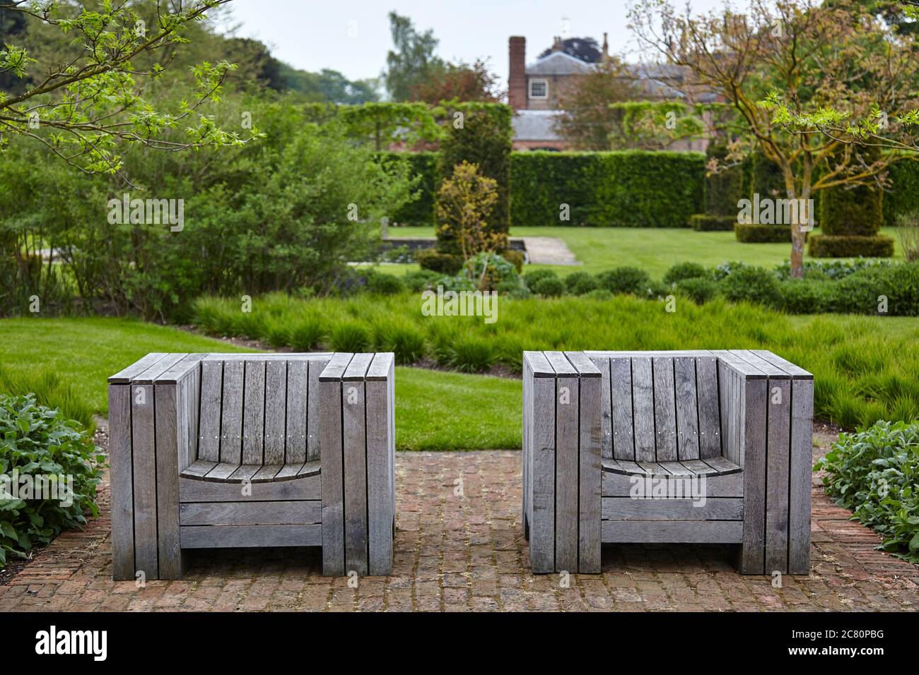 wo wooden garden chairs on paved terrace in the Walled Garden at Scampston Hall Stock Photo