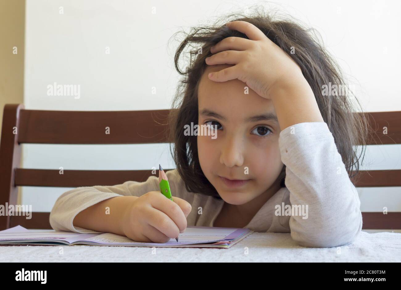 Elementary student makes her homework. She makes her own homework alone at home because of the schools  are on closed because of the corona pandemi Stock Photo