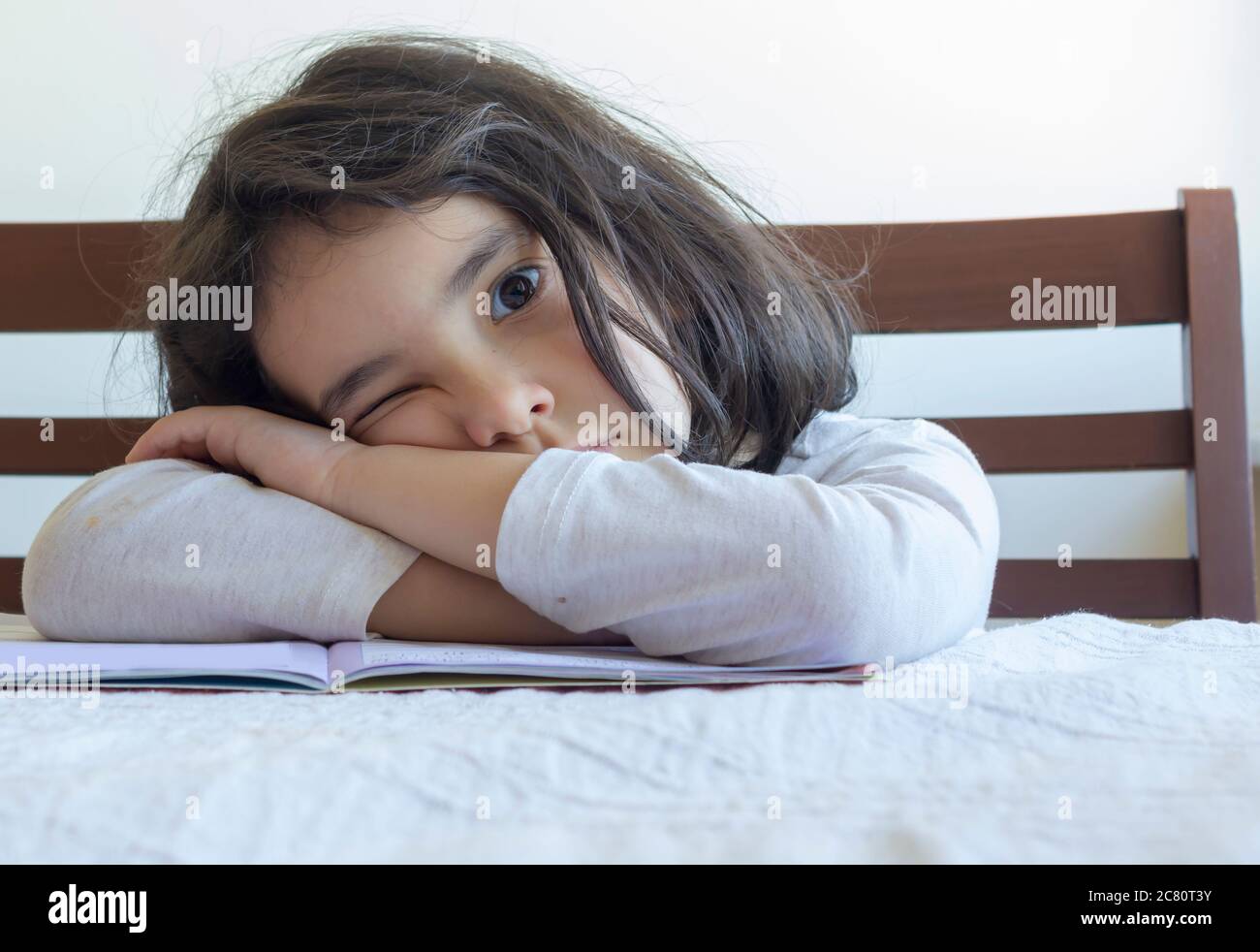 Elementary student makes her homework. She makes her own homework alone at home because of the schools  are on closed because of the corona pandemi Stock Photo