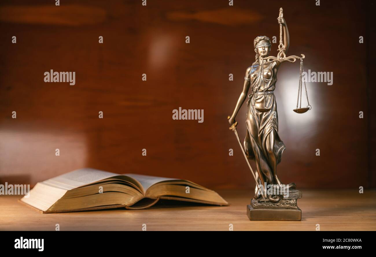 Statue of lady justice and a book on a brown background copy space for text Stock Photo