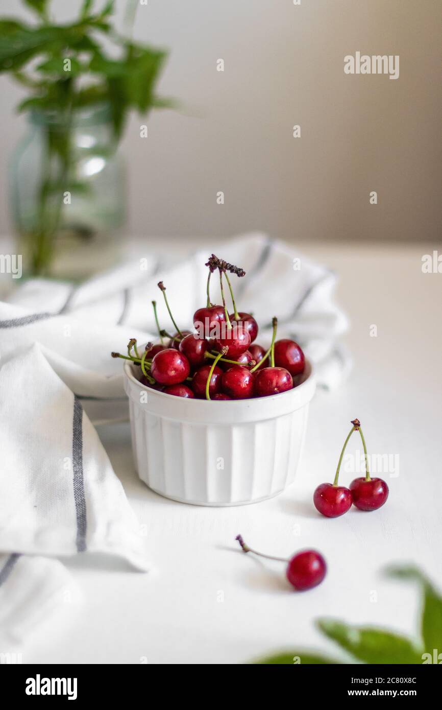 Fresh cherry in a ceramic bowl on white table. View from above. Vertical photo Stock Photo