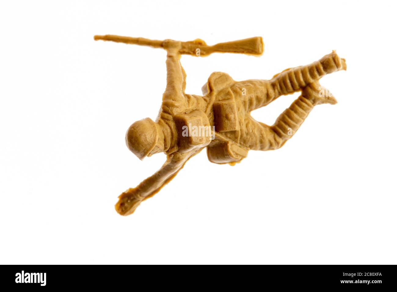 Airfix HO/00 scale model Japanese soldier figure from the 1960's against plain background. Close up of advancing WW2 soldier crawling with rifle. Stock Photo