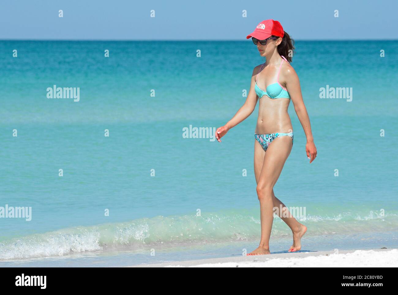 HOLMES BEACH, ANNA MARIA ISLAND, FL / USA - May 1, 2018: Beautiful Young Woman taking a leisure walk on the Beach enjoying a Beautiful Summer Day. Stock Photo