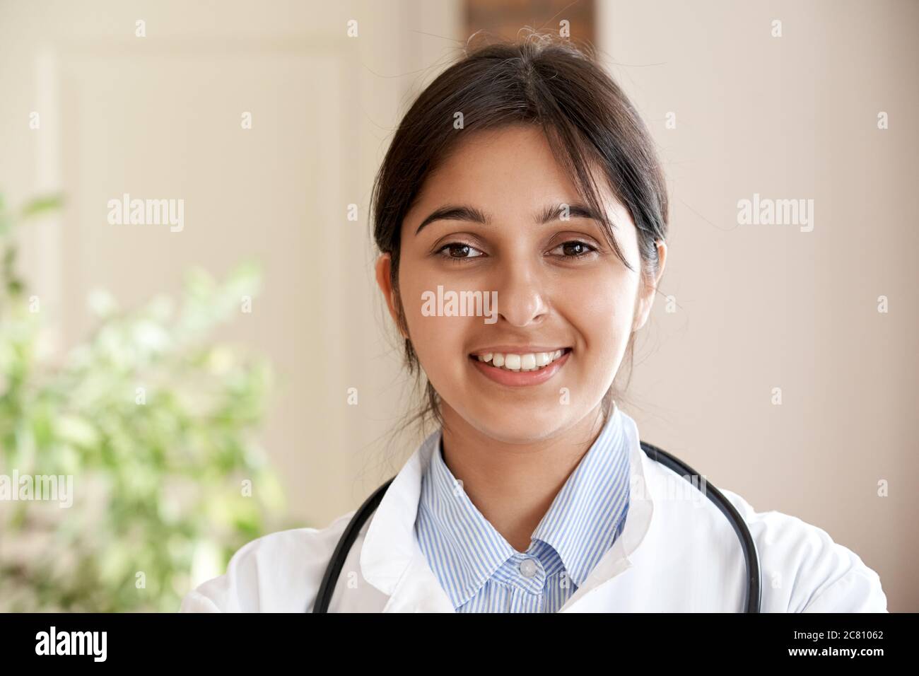 Smiling indian female doctor wear white coat look at camera, headshot