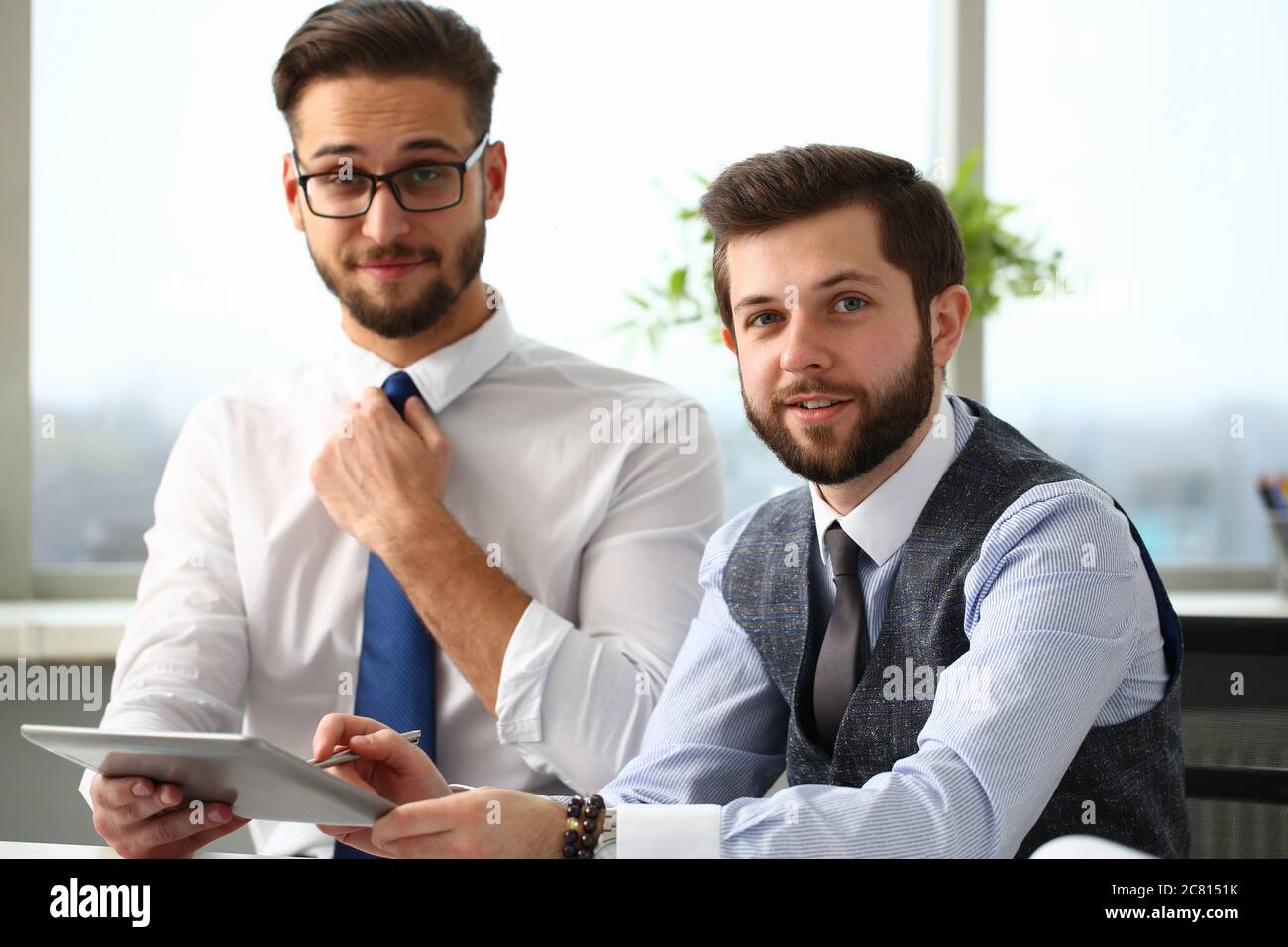 Two cheerful managers working in office with touchpad Stock Photo