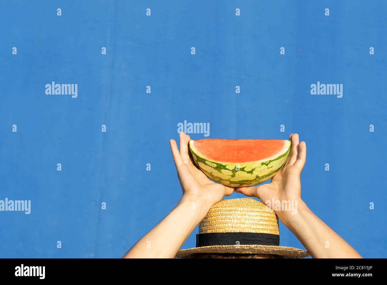 Young man in hat holding a piece of watermelon above his head. Summer, diet and weight loss concept. Stock Photo