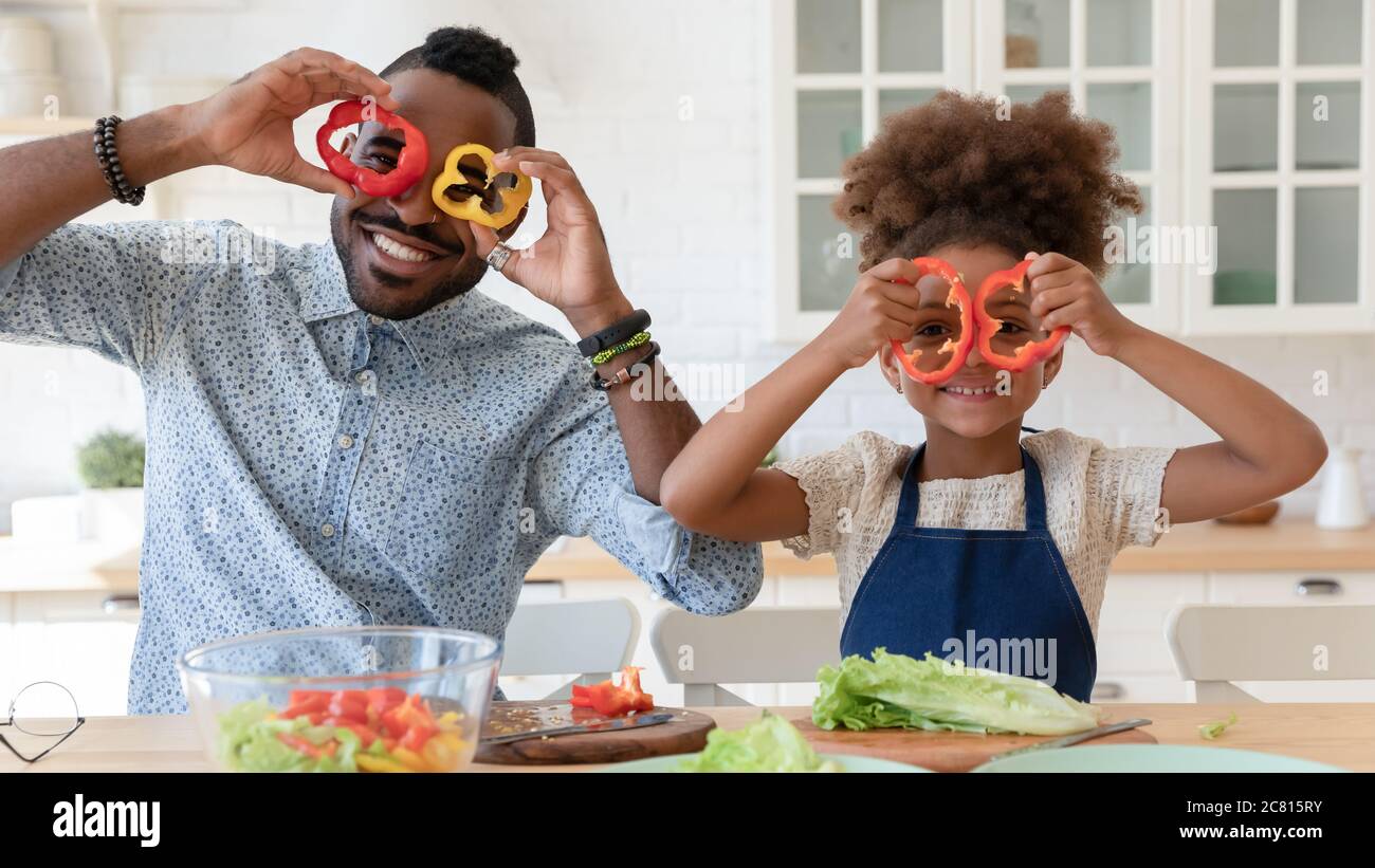 Portrait of smiling biracial dad and daughter have fun cooking Stock Photo