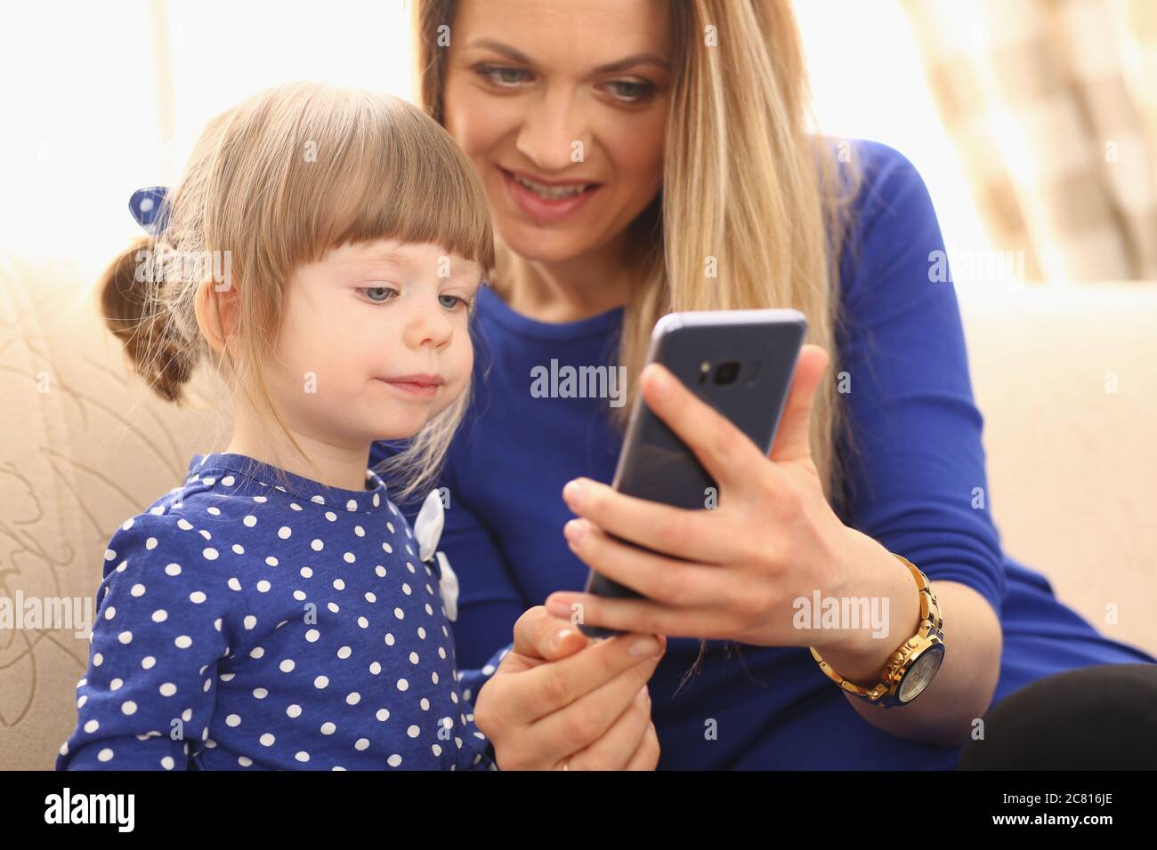 Cute little girl with smiling mom using smartphone Stock Photo - Alamy