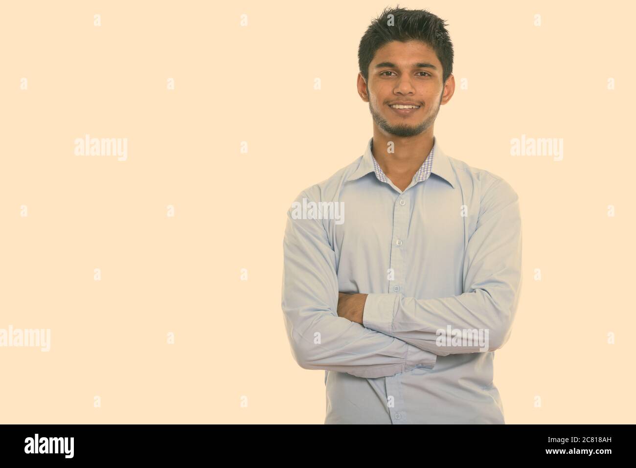 Studio shot of young happy Indian man smiling with arms crossed Stock ...