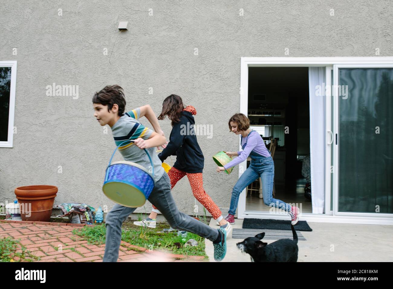 Siblings dash outside with their empty easter baskets to collect eggs Stock Photo