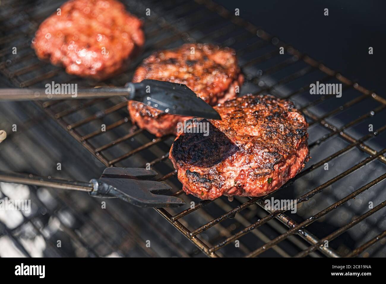 burger barbecue roasted on metal grill. The person cooking burger Stock Photo