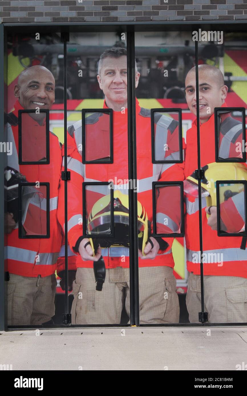 three male fire fighters on the the entrance of electric folding doors for emergency vehicles Stock Photo