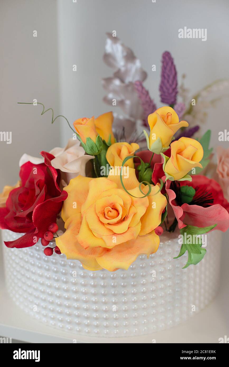 Elegant floral decoration for a wedding cake, covered in royal icing and symmetrically positioned sugar pearls, with an edible sugar paste roses Stock Photo