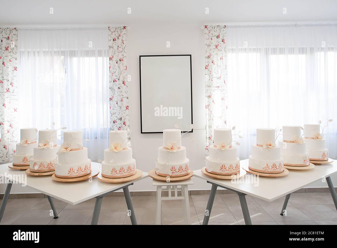 Wedding cake display with nine identical three tier cakes covered in royal icing with delicate and simple decoration, part of a baking workshop Stock Photo