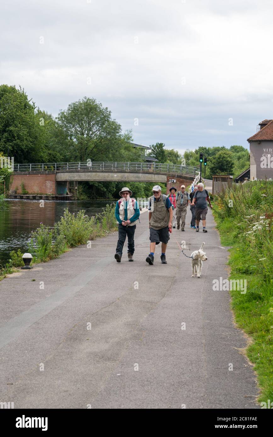A group of ramblers and a dog walking along the tow path of the Grand Union Canal head towards Coppermill Lock, Harefield, Middlesex, England, UK Stock Photo
