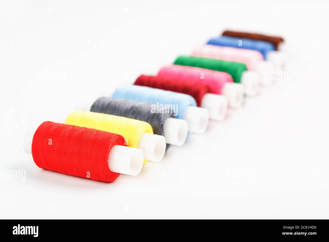 Sewing threads of different colors on reels on a white background. Free ...