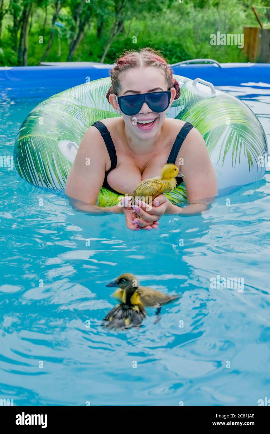 Young woman in backyard above ground swimming pool with duckling Stock Photo