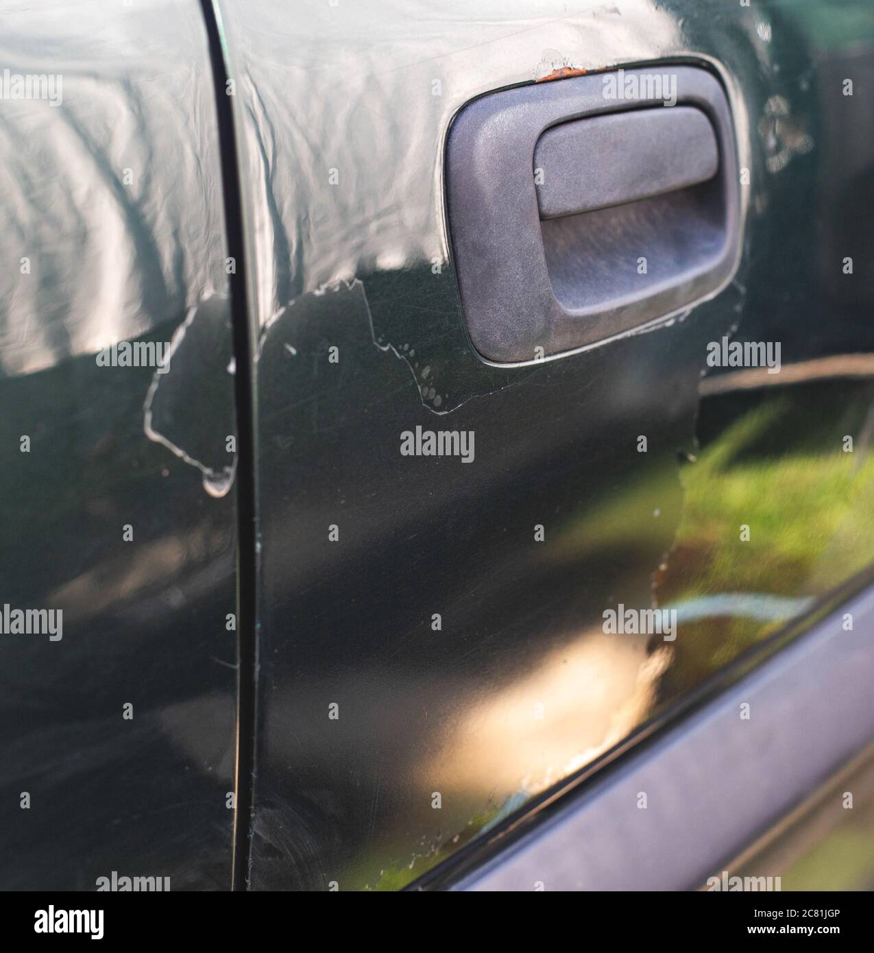 Peeling car paint from the passenger door of the car. Poor car painting